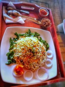 un plato de arroz y verduras en una bandeja roja en Ravan, en Tangalle