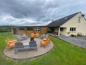 a backyard with a fire pit and chairs and a house at Sleeps 18 Double Decker Bus Hot Tub Sauna Cinema Pets in Irvinestown
