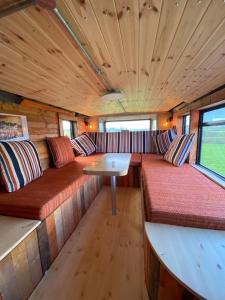 un wagon avec bancs et table dans l'établissement Sleeps 18 Double Decker Bus Hot Tub Sauna Cinema Pets, à Irvinestown