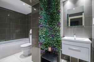 a bathroom with a green wall with flowers at Larger Groups Apartment with Garden and Parking in London