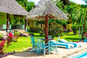 a patio with chairs and a table and a umbrella at Oasis Diani Beach Villas in Diani Beach