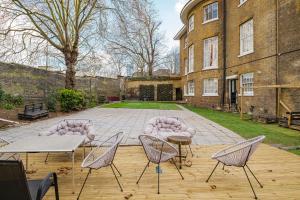 eine Terrasse mit Stühlen und Tischen vor einem Gebäude in der Unterkunft Larger Groups Apartment with Garden and Parking in London