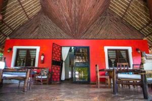 Zimmer mit einer roten Wand, Tischen und Stühlen in der Unterkunft Oasis Diani Beach Villas in Diani Beach