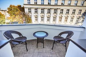 2 Stühle und ein Tisch auf einem Balkon mit einem Gebäude in der Unterkunft Art Deco Apartament dla 6 osób Chorzów/Katowice 6A in Chorzów