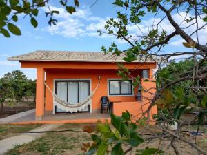 una pequeña casa naranja con una hamaca delante en Pousada Refúgio da Serra en Pirenópolis