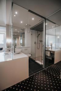 La salle de bains est pourvue d'une douche en verre et d'un lavabo. dans l'établissement Boutique Hotel am Rathaus - Reblaus, à Ulm
