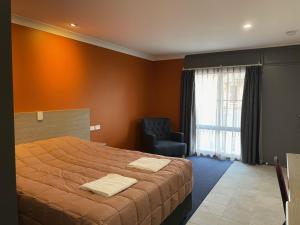 sypialnia z dużym łóżkiem i krzesłem w obiekcie Homestead Motel w mieście Dubbo
