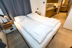 Cama blanca grande en habitación con baño en Hrimland Apartments, en Akureyri