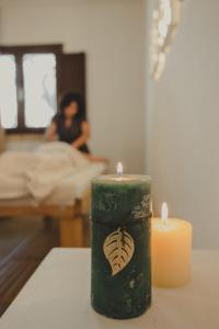 una candela su un tavolo con una donna in un letto di Marenea Suite Hotel - CDSHotels a Marittima