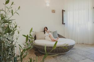a woman sitting on a bed in a room at Marenea Suite Hotel - CDSHotels in Marittima