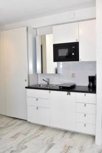 a white kitchen with a sink and a microwave at 010 Studio City Center Rotterdam in Rotterdam