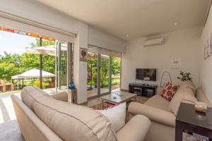sala de estar con 2 sofás y TV en Windsong Living - Eagle Owl, en Krugersdorp