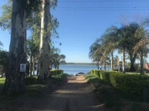 a dirt road with trees and a body of water at Casa frente al lago en barrio privado in Almafuerte