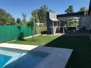 un patio trasero con piscina y una casa en Casa frente al lago en barrio privado en Almafuerte
