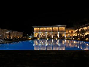 - une grande piscine en face d'un bâtiment la nuit dans l'établissement Lagoon Sarovar Premiere Resort - Pondicherry, à Pondichéry