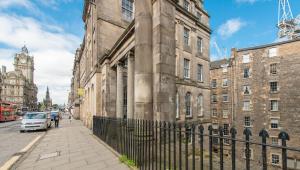 un ancien bâtiment en pierre avec une clôture à côté d'une rue dans l'établissement Downtown and central 1 bed in Edinburgh, sleeps 4, à Édimbourg