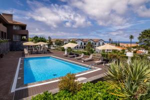una piscina en un hotel con sillas y sombrillas en The Lince Nordeste, en Nordeste