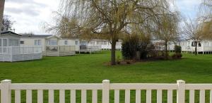 einen weißen Zaun vor einem Hof mit Häusern in der Unterkunft Willow Lodge in South Cerney