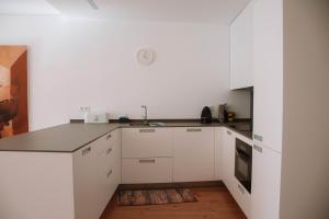 a kitchen with white cabinets and a wooden floor at Just Like Home - Casinhas da Vila T2 em Caminha in Caminha