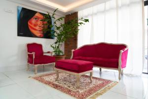 uma sala de estar com duas cadeiras e um sofá vermelho em Hôtel Amazonia Cayenne Centre em Cayenne