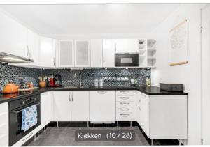 a kitchen with white cabinets and black counter tops at privateroomintheapartment in Oslo