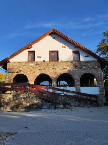 um edifício de tijolos com janelas arqueadas e uma cerca em Holló és Bárány Vendégház em Herend