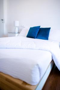 un grande letto bianco con cuscini blu sopra di B&B Best Hostel Milano a Milano