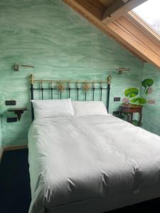 a bedroom with a white bed with a green wall at Posada d'Àneu in Esterri d'Àneu