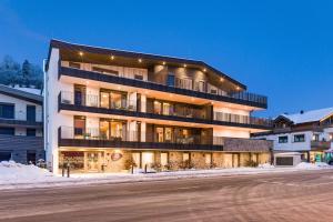 un grand bâtiment sur le côté d'une rue dans l'établissement REMIND Apartements Brixental, à Brixen im Thale