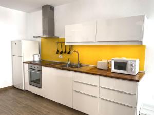 uma cozinha com armários brancos e um micro-ondas em CASA GABRIELA em Orzola