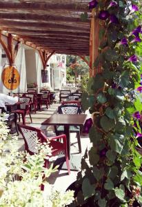 un patio con mesas, sillas y flores púrpuras en L'Auberge d'Eygliers, en Eygliers