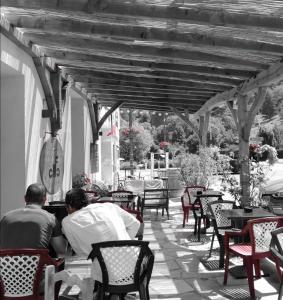 dwóch mężczyzn siedzących przy stołach i krzesłami na patio w obiekcie L'Auberge d'Eygliers w mieście Eygliers