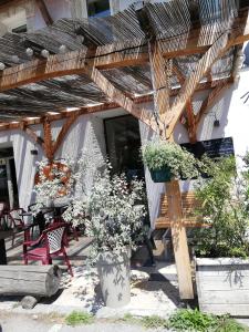 a wooden pergola with a table and some plants at L'Auberge d'Eygliers in Eygliers