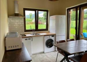 a kitchen with a sink and a washing machine and a table at BUNGALOW LA COCINA in Valdaliga 
