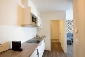 a kitchen with a sink and a microwave at Smart & Stay Aparthotel Saarbrücken Süd - Self-Check-In - Free Parking in Saarbrücken