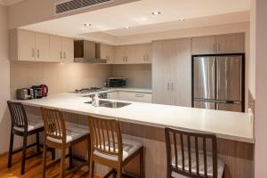 a kitchen with a counter with three chairs and a counter top at The Lookout in Dunsborough