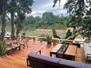 een terras met banken en tafels en uitzicht op een rivier bij Moonlight Champa Riverview in Luang Prabang