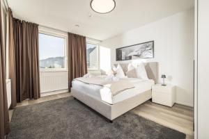 a white bedroom with a large bed and a window at MaxStudio Premium Apartment Zillertal mit Bergblick in Schlitters