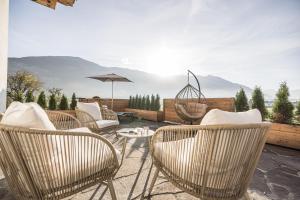 a patio with chairs and a table and an umbrella at MaxStudio Premium Apartment Zillertal mit Bergblick in Schlitters
