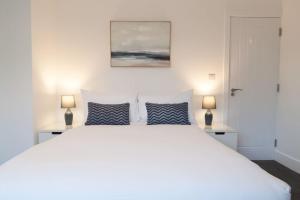 een slaapkamer met een groot wit bed met 2 lampen bij The Spitfire - Renovated 3-bed house in Cheltenham, SLEEPS 8 in Cheltenham