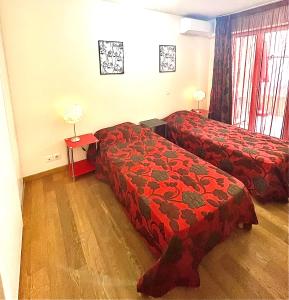 Cette chambre d'hôtel comprend 2 lits avec des draps rouges. dans l'établissement Jolie 3 pièces avec terrasse au vieux port, à 2 pas des plages et du palais., à Cannes
