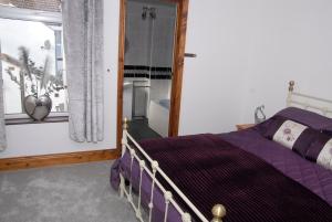 a bedroom with a purple bed and a window at Seashells Cottage in Gorleston-on-Sea