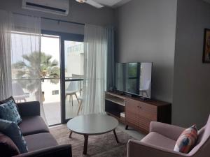 een woonkamer met een bank, een tv en een tafel bij Aqua View Apartments in Bijilo