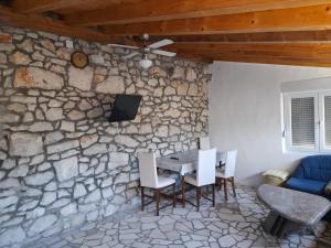 ein Esszimmer mit einer Steinmauer sowie einem Tisch und Stühlen in der Unterkunft Kamena Kuca Family Rodin in Čapljina