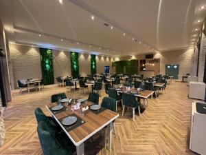 ein Esszimmer mit Tischen, Stühlen und grünen Pflanzen in der Unterkunft Castle Resort Spa Hotel in İsmayıllı