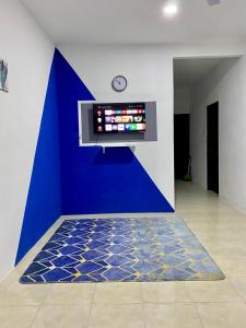 a room with a blue wall and a clock on a wall at Azfar Homestay in Kangar
