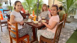 tres chicas sentadas en una mesa en un restaurante en Hospedaje Ola Marina, en Máncora