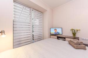 a white bedroom with a bed and a television at Sveciu Namai Alanta in Palanga