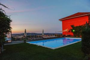 a swimming pool with chairs and a red building at Agriturismo Paitin in Alba