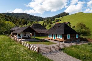 eine Gruppe von Cottages auf einem Feld mit einem Zaun in der Unterkunft Hygge Loft Bucovina in Vama